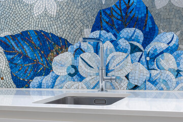Close-up of a metal faucet with a metal sink in a kitchen of an apartment 