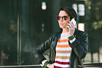 Fototapeta premium Young millennial female has her cell phone to her ear listening - City - Serious face - Daytime