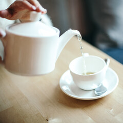 pour tea from a teapot into a white Cup, white kitchen utensils, cafe service concept, teapot with a white mug, aroma, taste, break, Breakfast