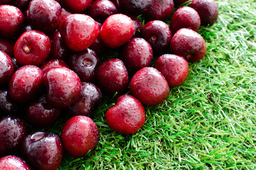 red fresh cherries on green grass, close view