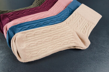 different colored women's socks on a dark wooden background. Lot of socks.