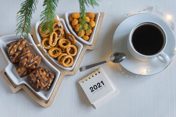 Calendar for 2021, a cup of coffee and various sweets on a white background.
