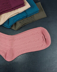 different colored women's socks on a dark wooden background. Lot of socks.