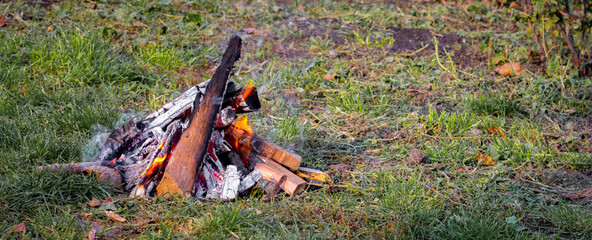 Bonfire with unfolded firewood in the garden on the grass