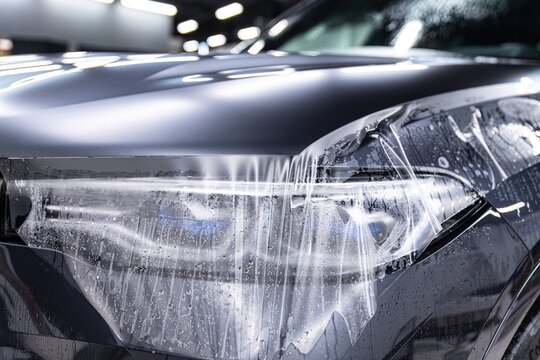 Car detailing specialist installing protective transparent foil
