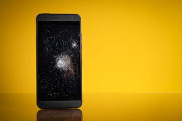 Zerstörtes Mobiltelefon vor gelben Hintergrund