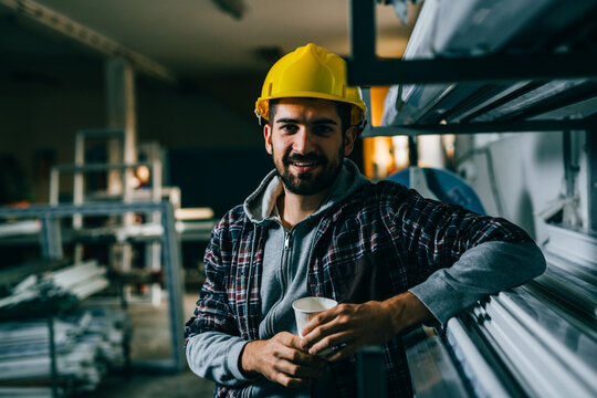 Industrial Worker On Lunch Break, Holding Cup Of Coffee And Looking At Camera