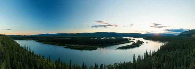 Obraz na płótnie Canvas Gorgeous View of Scenic Winding River, surrounded by Forest Valley and Mountains in Canadian Nature at Dusk. Aerial Drone Shot. Taken near Klondike Highway, Yukon, Canada.