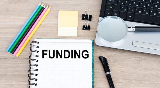 Funding - the inscription of text on the Notepad on the desktop next to the laptop.