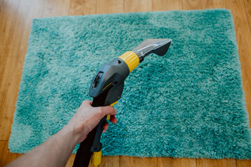 carpet cleaning, vacuum cleaner tube in women's hands cleans the carpet, the concept of cleanliness in the house, apartment cleaning, textile cleaning machine, order