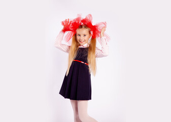 schoolgirl with bright tulle bows on her head in school clothes on a white background