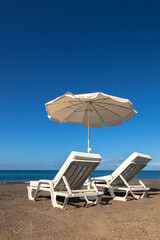 Pair of sun loungers and parasol on Duque Norte beach in Costa Adeje, Tenerife