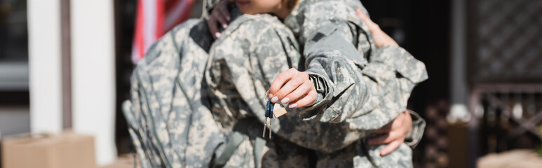 Cropped view of keys with blurred military couple embracing on background, banner © LIGHTFIELD STUDIOS