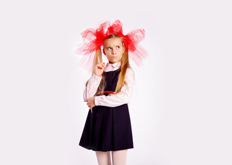 schoolgirl with bright tulle bows on her head in school clothes on a white background