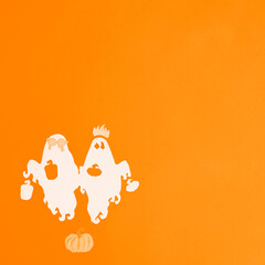 Ghosts and pumpkins are cut from white paper on a orange background. Square photo of paper art for your scary Halloween design. There is a place for text.