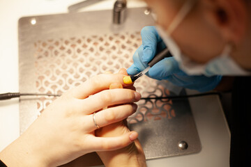 Nail salon. A young woman does a colored manicure.The manicurist covers her nails with nail Polish. A woman does a manicure and applies nail Polish
