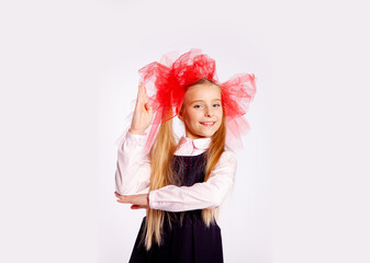 schoolgirl with bright tulle bows on her head in school clothes on a white background