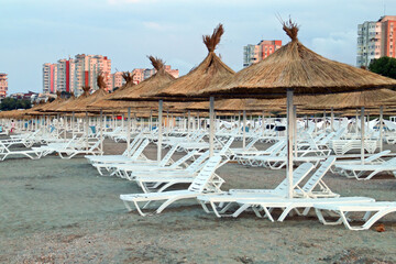 Sombrillas y tumbonas en una playa solitaria al atardecer. Playa tres zapatillas (rumano; Plaja...