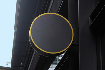 Modern blank generic outdoor round sign outside a restaurant or retail store. Dark grey in colour