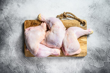 Fresh raw chicken thighs, legs on a chopping Board. Gray background. Top view.