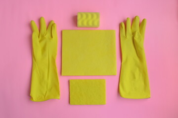 Yellow rubber gloves and different washcloths and cleaning rags on pink background. Cleaning or housekeeping concept background. Flat lay, Top view.