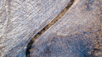 Aerial view of curved road in the snowy mountains. Top down view of frozen winter forest and a curvy road