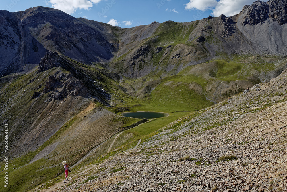 Wall mural alps mountains landscape view with little lake (lac de souliers). girl tourist with hat and camera l