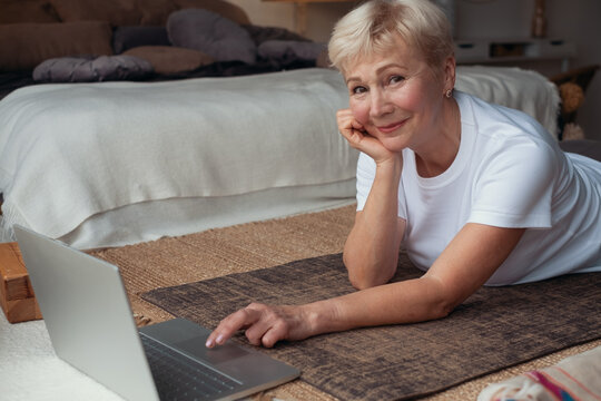 Active Senior Woman Surfing In Internet On Yoga Mat.