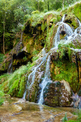 Fototapeta na wymiar Details of waterfall Cascade des Tufs in Jura Mountains area. Woter flowing in unique waterfall. France, Europe.
