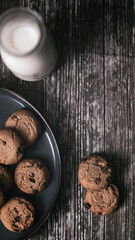 Flat lay of chocolate chip cookie and a bottle of milk with crumbs on wooden table simple morning breakfast snack c