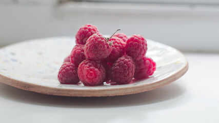 Ripe juicy raspberries lies on a plate. Ripe organic raspberries close-up.