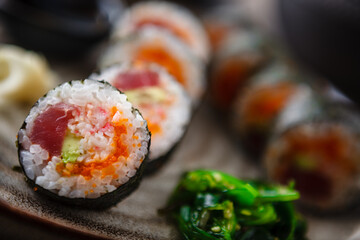 Sushi maki rolls with tuna, flying fish caviar, crab, avocado on a plate with chopsticks, soy sauce, wasabi and ginger. Japanese traditional food closeup served for lunch in modern gourmet restaurant