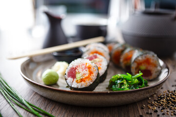 Sushi maki rolls with tuna, flying fish caviar, crab, avocado on a plate with chopsticks, soy sauce, wasabi and ginger. Japanese traditional food closeup served for lunch in modern gourmet restaurant