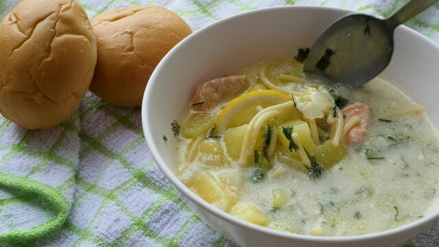 Mixes ingredients in hot chicken and vegetables soup. Restaurant kitchen concept. Red fish meat slices, noodles, boiled potatoes, sour cream and lemon, bread