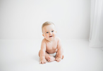 Cute baby boy sitting in diaper on white background
