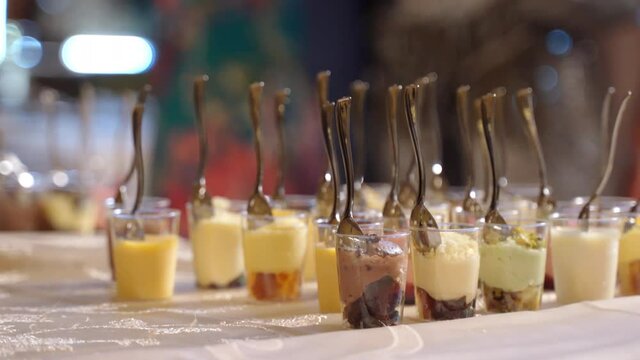 Close-up of catering banquet menu on buffet table, small goblets filled with fruits ice-cream and jellied desserts. Preparation of candy bar at kids party, birthday or wedding event celebration