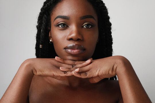Close-up portrait of young black attractive woman, posing over white background. Skin care concept.