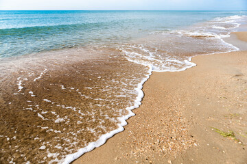 Waves with sea foam on a sandy beach