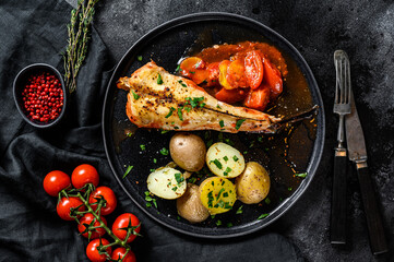 Cooking in tomatoes monkfish fish with baked potatoes. Fresh seafood. Black background. Top view