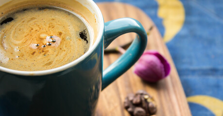 A cup of aromatic coffee stands on a wooden table.