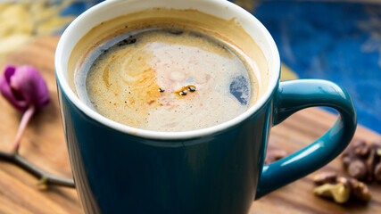 A cup of aromatic coffee stands on a wooden table.