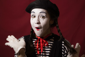 Beautiful mime girl grimaces and holds her pigtails with her hands.