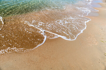 Waves with sea foam on a sandy beach