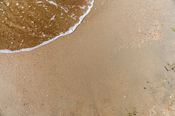 Waves with sea foam on a sandy beach