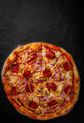 Obraz na płótnie Canvas Pizza with Mozzarella cheese, ham, tomato sauce, pepper, pickled cucumbers and onion. Italian pizza on Dark grey black slate background