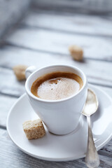 Cup of coffee on bright wooden background. Close up. 
