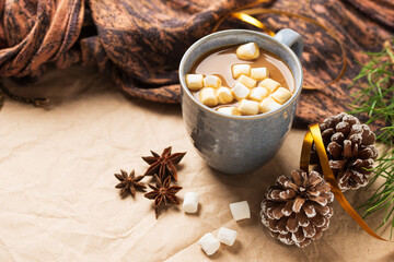 A Cup of coffee or cocoa with marshmallows with Christmas tree or New year decor. Winter still life with a warm drink, scarf, anise stars and cones copy space