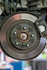 The hub of a wheel in a car service. Suspended car with no wheels. Suspension of car in service room.The car lift up by lifter for maintenance suspension and cleaning parts. Close up. vertical photo