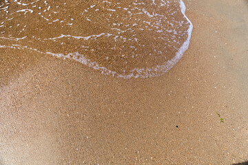 Waves with sea foam on a sandy beach