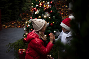 Happy family, young pretty woman with child spend time together outdoor at the background decorated...